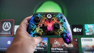A person holding up the PowerA Fusion Pro Wireless Controller in front of an Xbox home screen