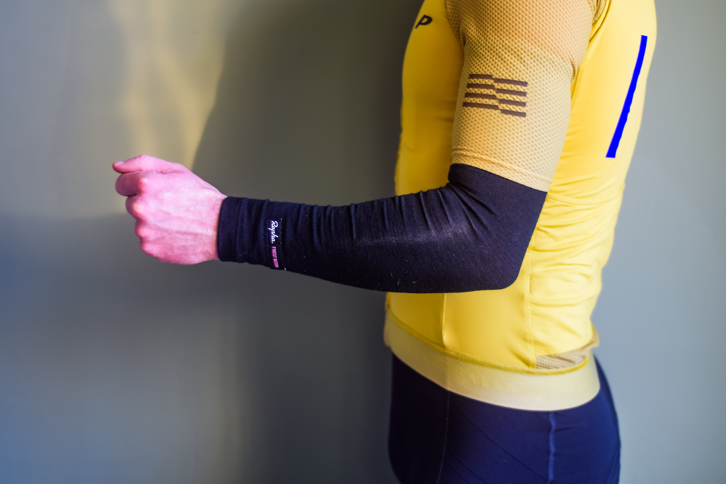A man in a yellow cycling jersey wearing black arm warmers