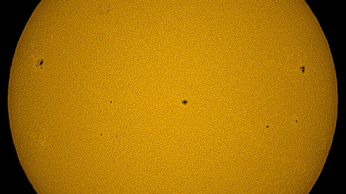 A closeup of the yellow solar surface, showing three dark sunspots, as imaged by the Unistellar eQuinox 2 smart telescope.
