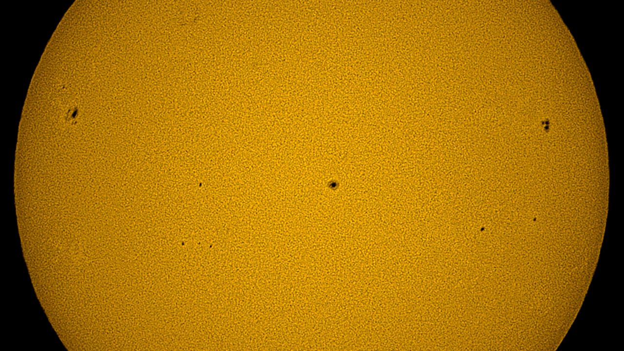 A closeup of the yellow solar surface, showing three dark sunspots, as imaged by the Unistellar eQuinox 2 smart telescope.