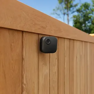 A Blink Outdoor 4 security camera attached to a wooden fence