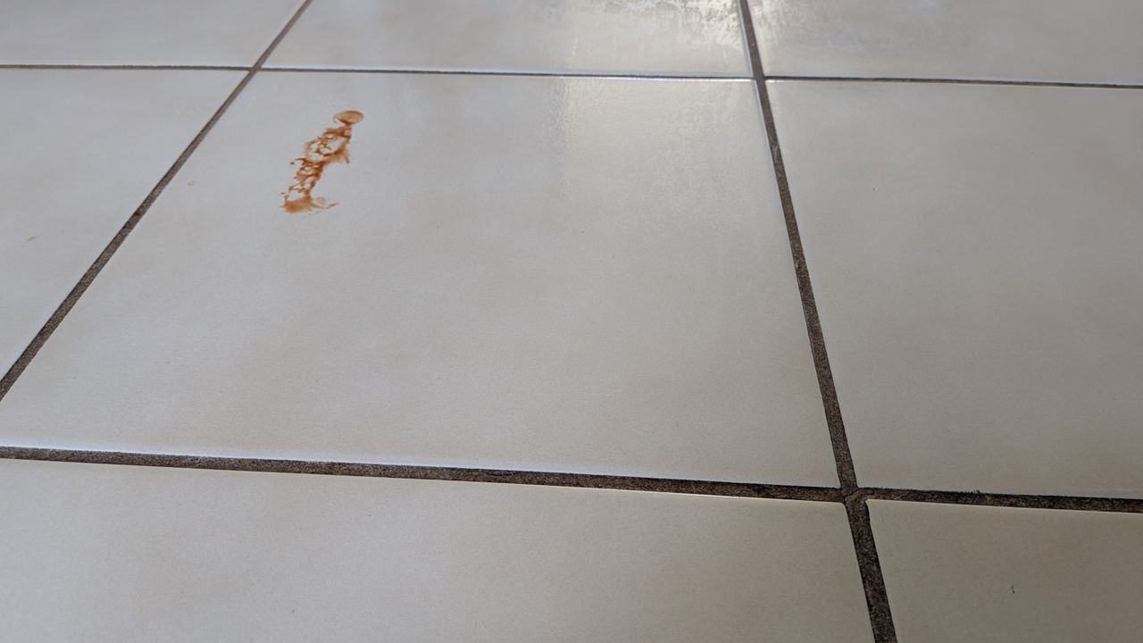 Remnant of ketchup on a tiled floor during the mopping test