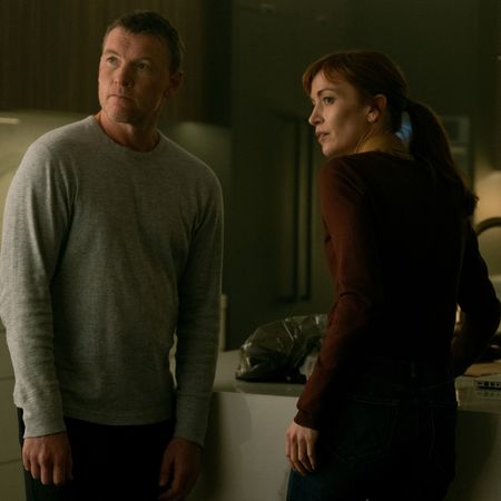 sam worthington as david and britt lower as rachel looking nervous over their shoulders in a kitchen in i will find you