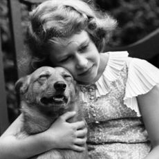 Queen Elizabeth hugging a dog as a child