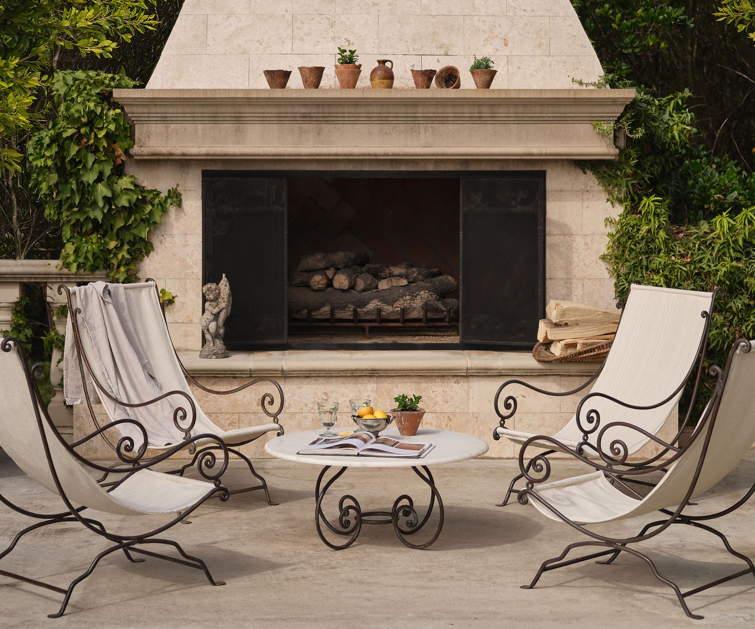 large patio with a huge stone outdoor fireplace with wrought iron and canvas deck chairs and a matching curved round coffee table