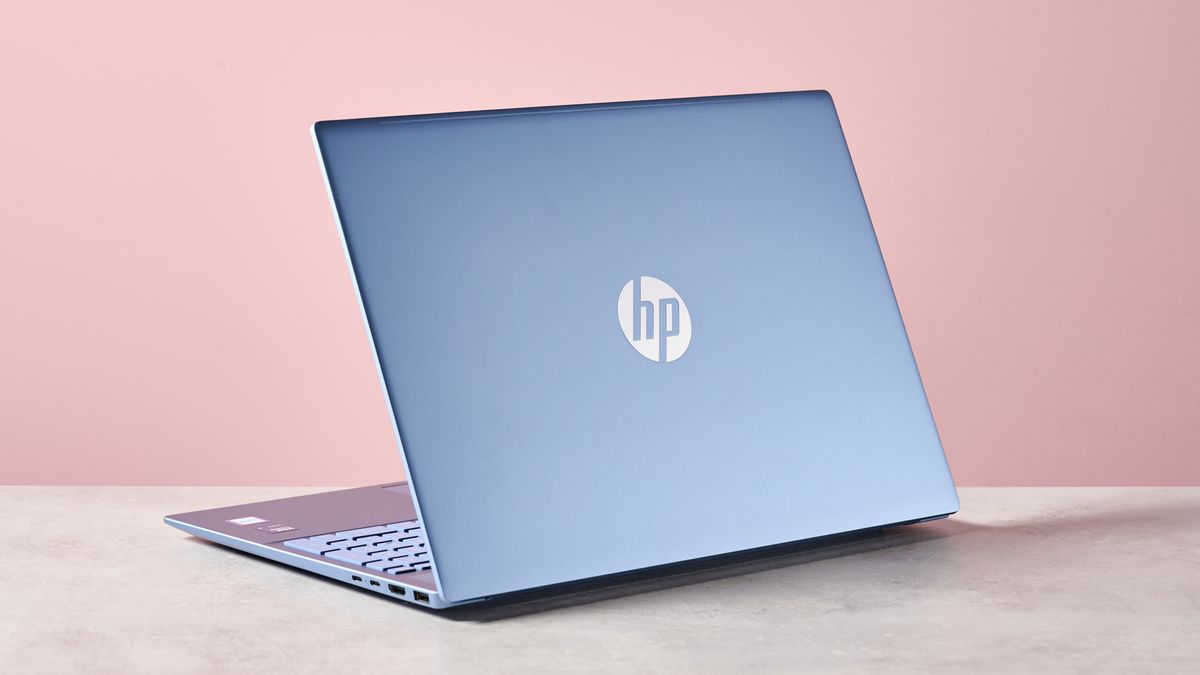 Three-quarter rear view of HP Pavilion 16, open on a desk with pink wall in background