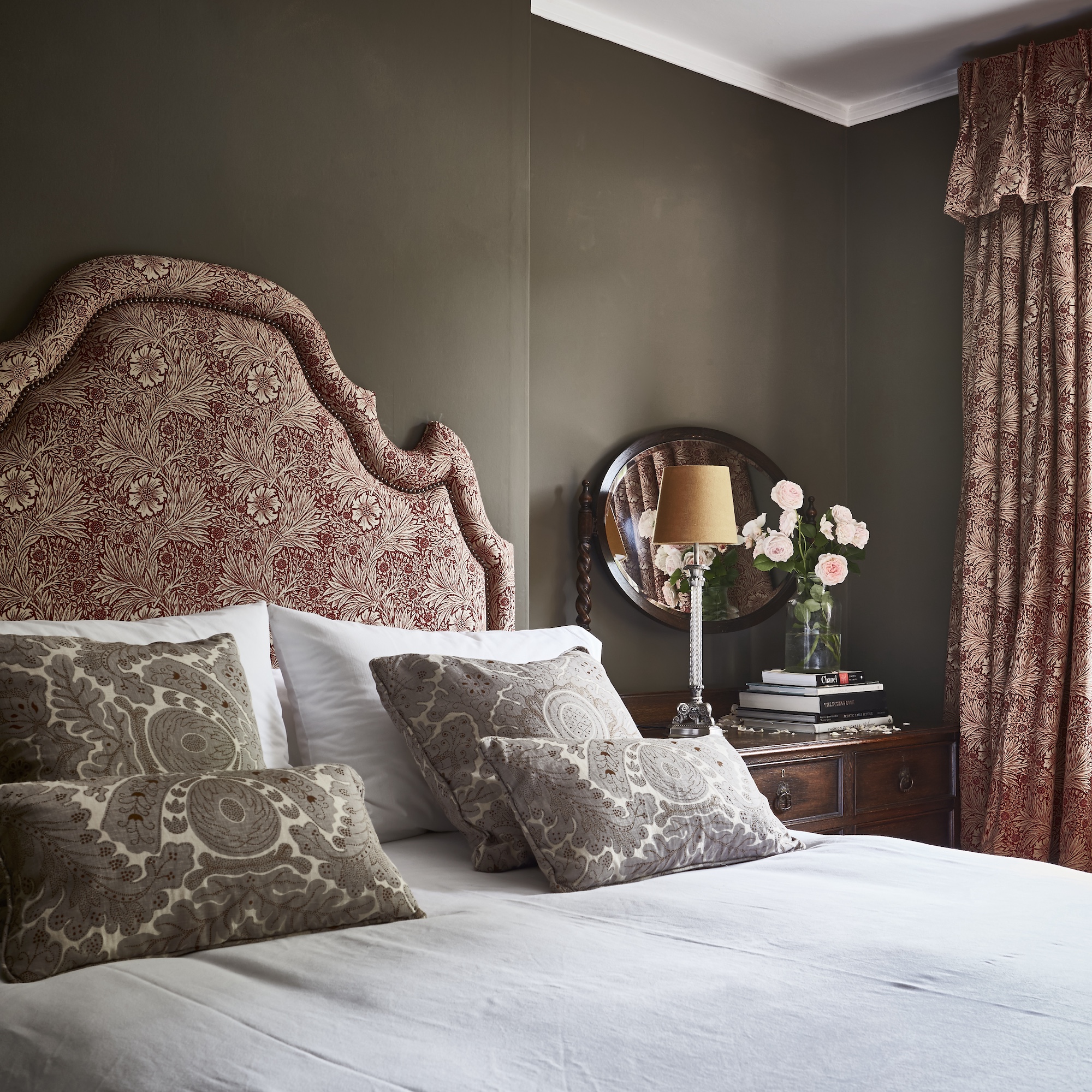bedroom with brown painted walls and large upholstered headboard in terracotta fabric