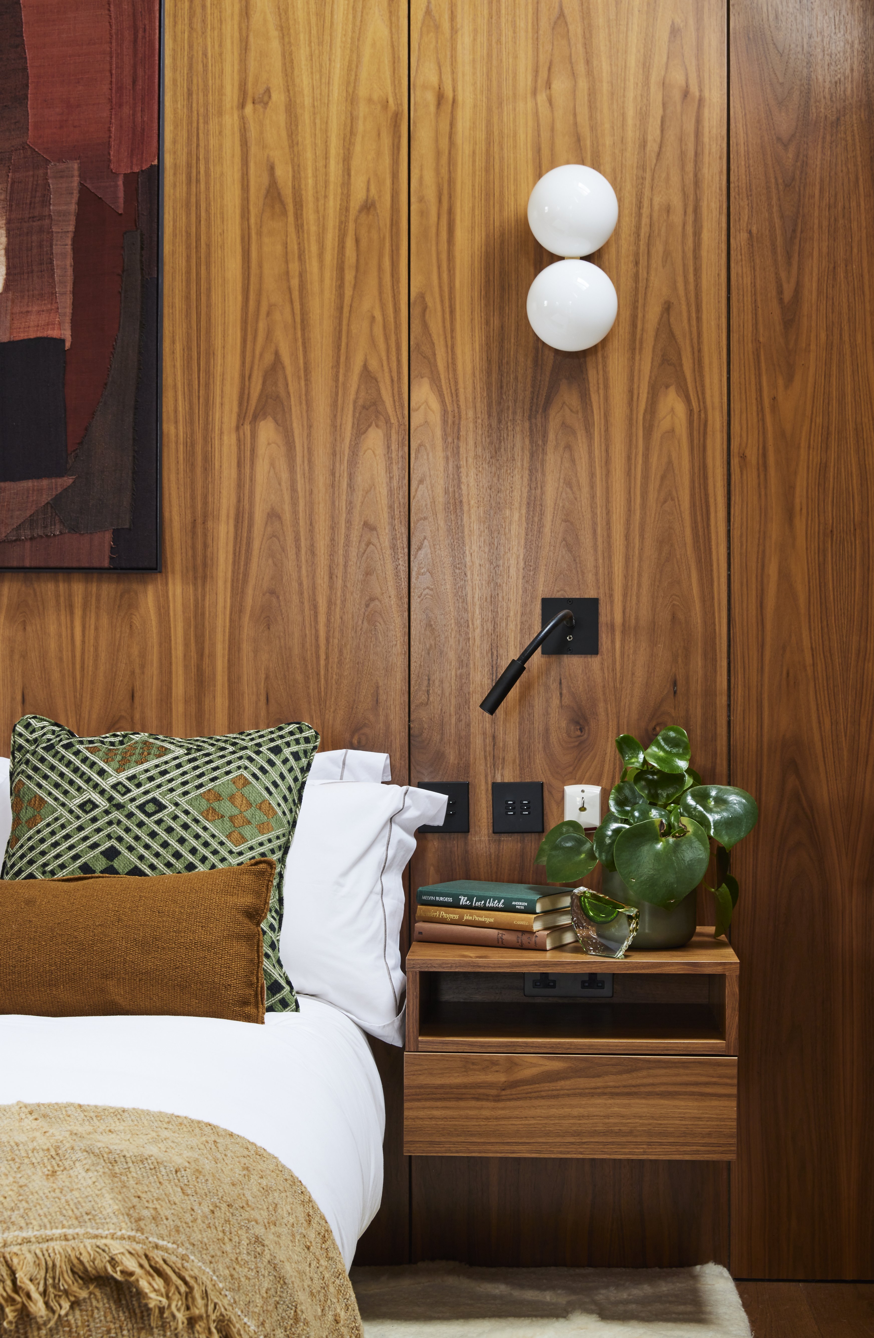 A bed surrounded by warm wood with a matching side table and complementary bedding