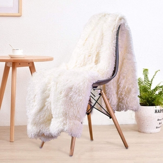 A fluffy faux fur throw blanket on a dining room chair