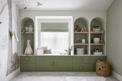 A kids room with built in storage on one wall around the window