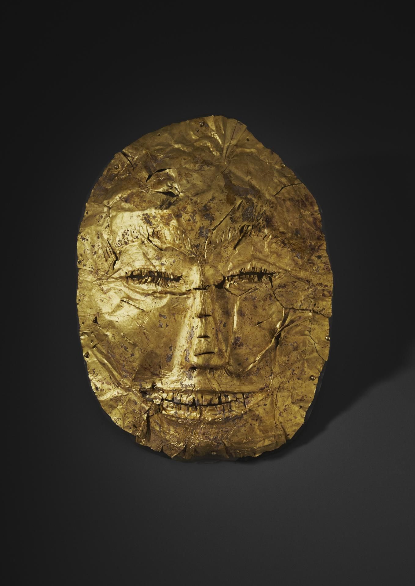 a humanlike gold mask against a black background