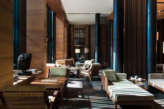 A sophisticated ski hotel lounge channels a retro vibe via modernist furnishings in wood and pale green textile and sculptural accents.