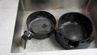 Parts of the air fryer in a sink being cleaned after using an air fryer