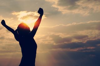 Confident woman with arms raised in the air.