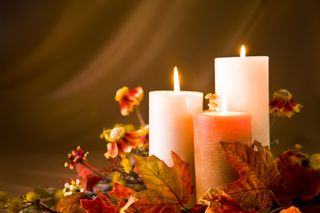 Candles surrounded by autumn leaves.