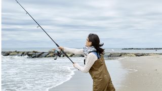 Woman casting fishing rod into sea