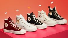 A selection of Converse trainers placed on a pink box with love heart illustrations.