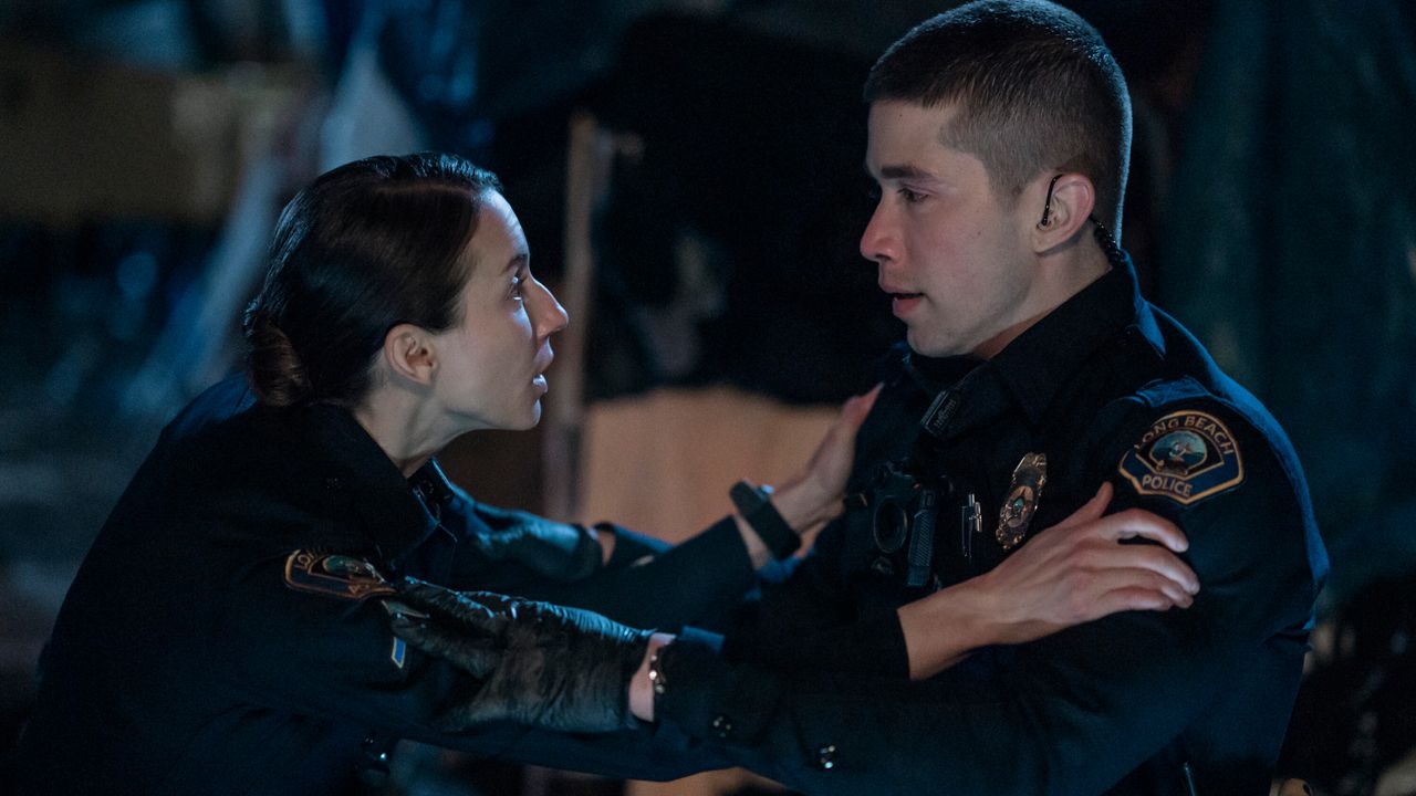 A female cop (Troian Bellisario) holds a male cop&#039;s (Brandon Larracuente) arms, in &#039;On Call.&#039;