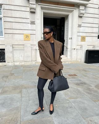 @nlmarilyn wearing a brown blazer, stirrup leggings, and black court shoes.
