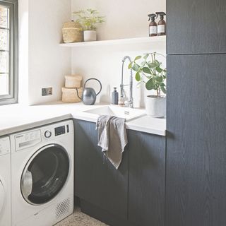 White kitchen with dark wooden cabinets, a washing machine, and a dish cloth laying on the side