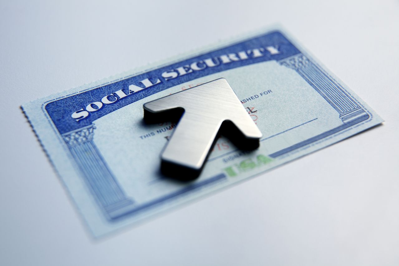 An upwardly pointing arrow rests on top of a social security card.