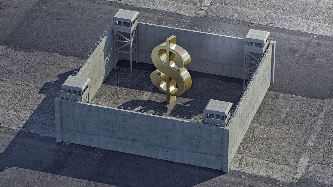 A dollar sign is surrounded by walls topped with barbed wire.