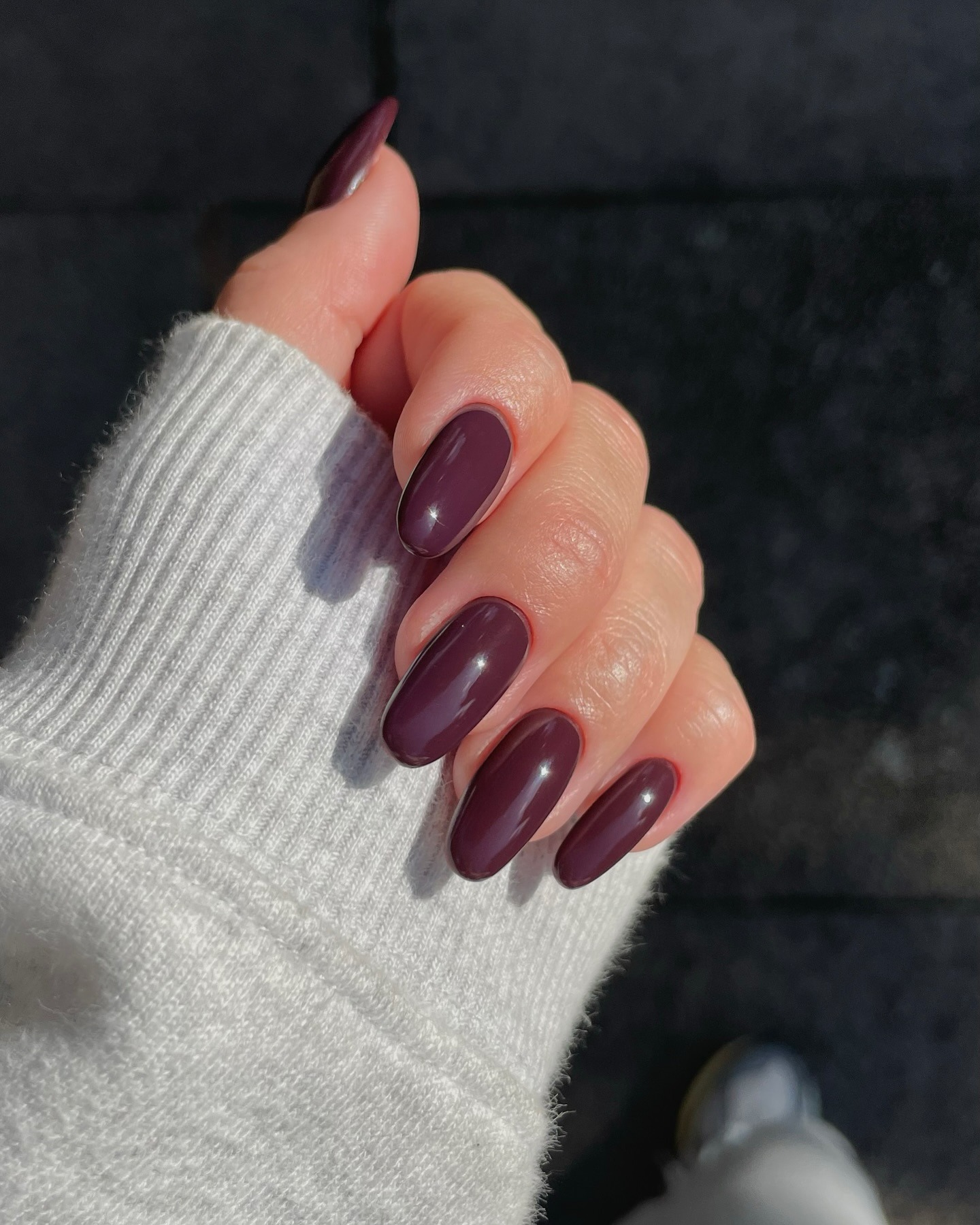 A long, oval-shaped aubergine manicure