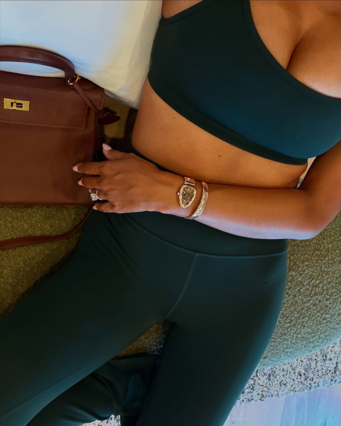Woman wearing green athleisure set and Bulgari Serpenti cocktail watch, one of the biggest jewelry trends of 2026.
