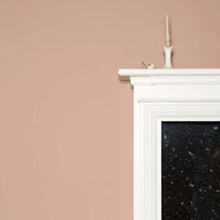 plaster pink wall with white and black fireplace