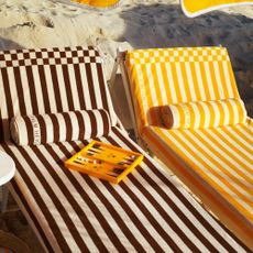 Two Palm Heights sun loungers covered in the striped towels from the H&M collection with the backgammon set on top