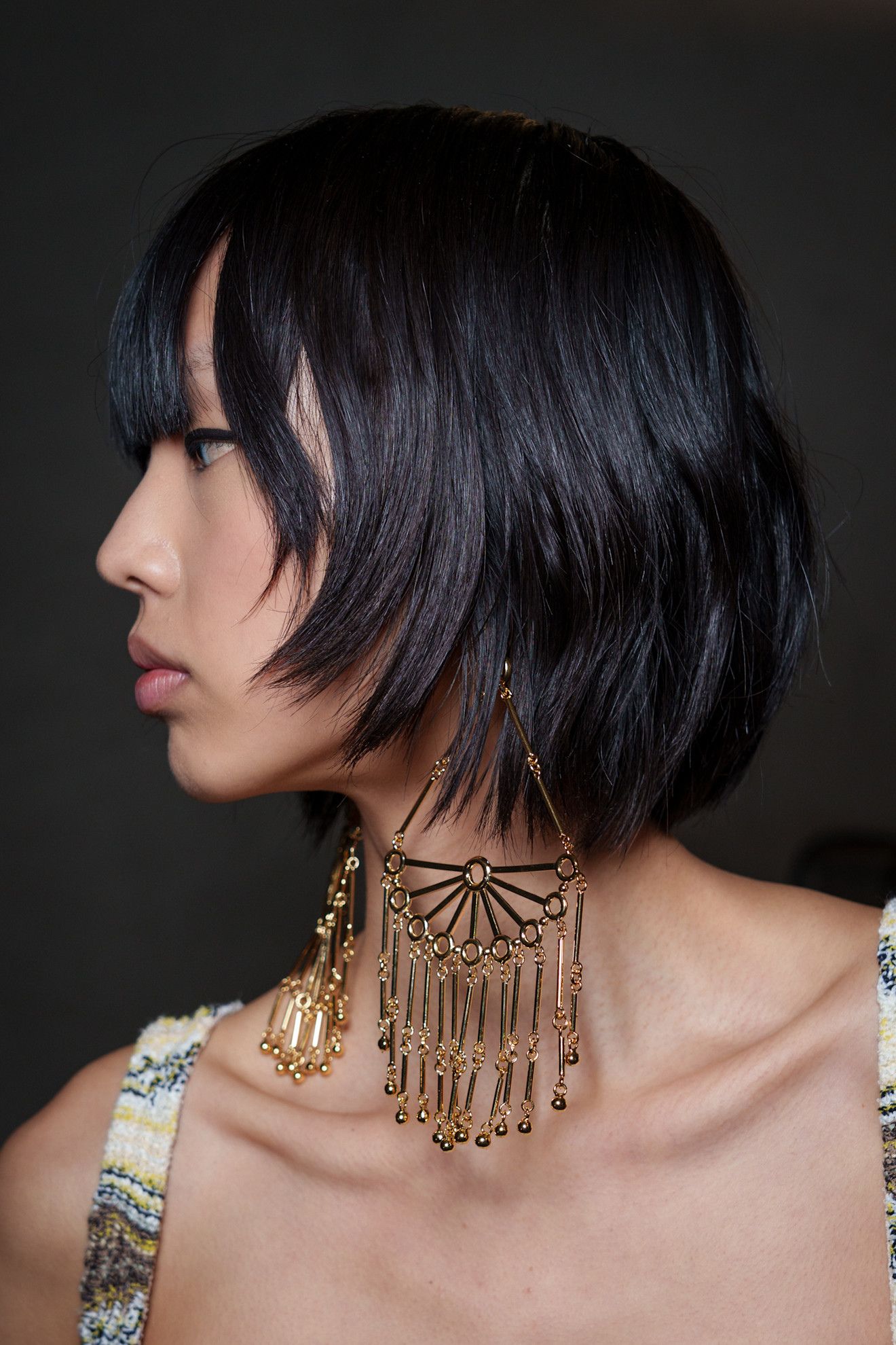 A model at Missoni SS26 show weaing super oversized earrings with a feathered bob hairstyle