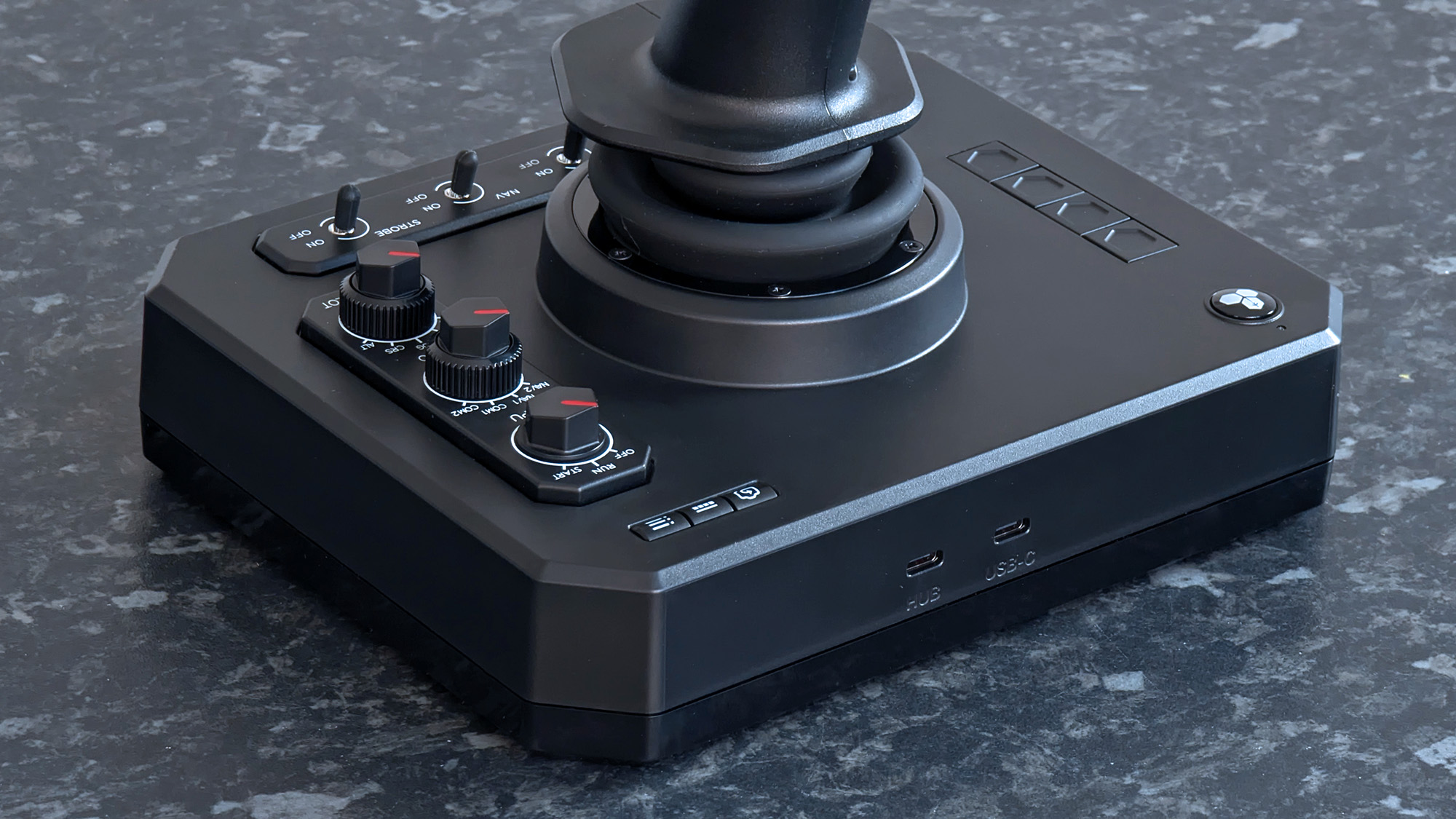 Rear USB-C ports shown alongside switches on a Honeycomb Aeronautical Foxtrot Aviation Stick, placed on a marble-patterned countertop