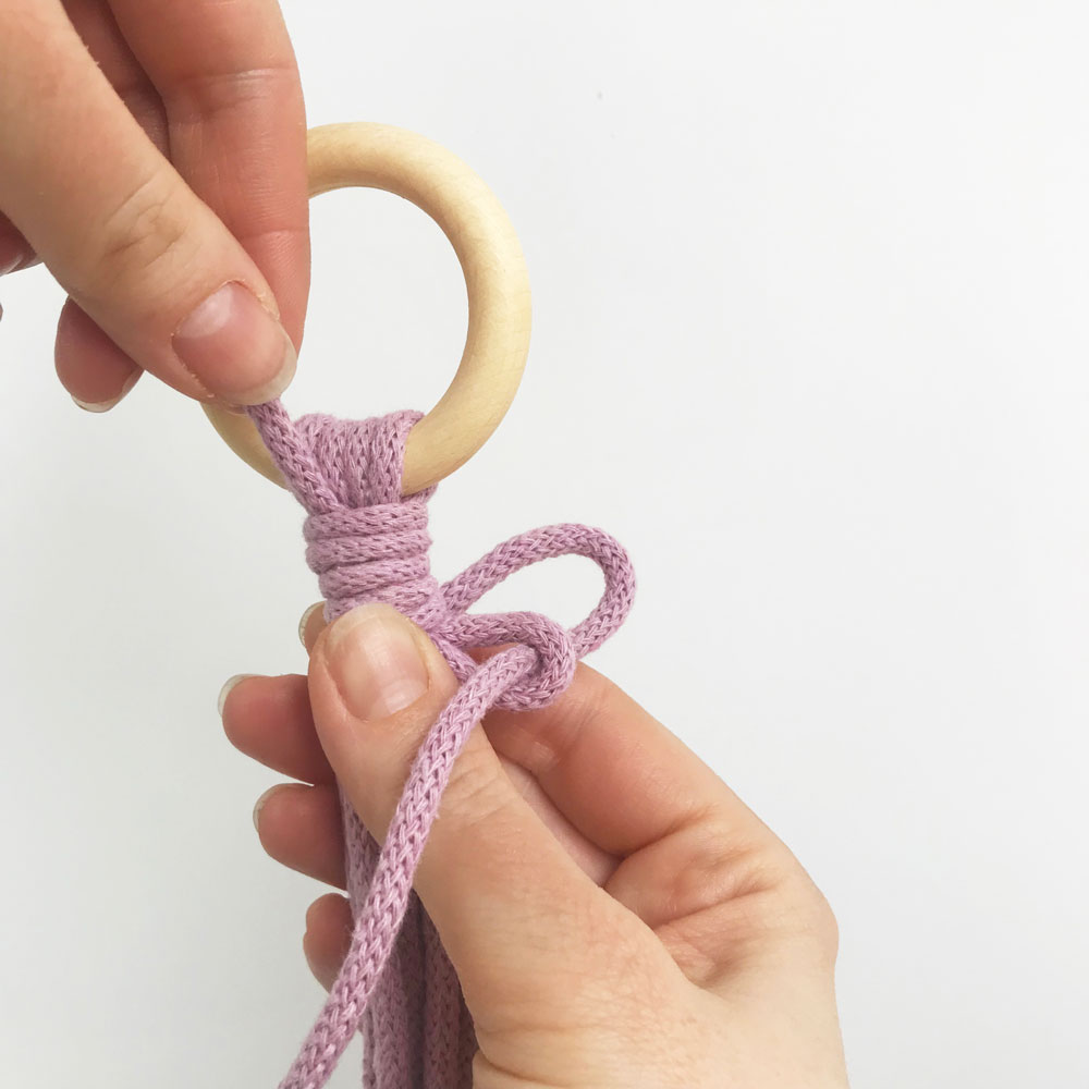 hand holding purple cord in wooden ring