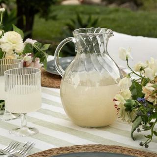 A pitcher full of lemonade on an outdoor dining table