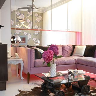 living room with pink sofa and grey and pink cushions and white wall and flower vase