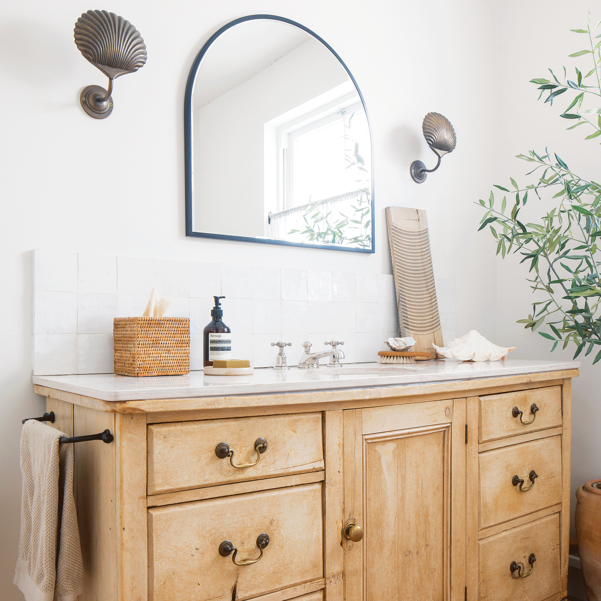 a neutral bathroom with a large vanity unit. mirror and antique shell-style wall lights