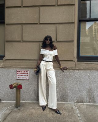 Sophisticated Fashion Trends: @emmanuellek_ wears a draped off-the-shoulder top tucked into cream wide-leg trousers