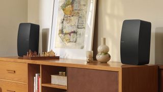 Two Sonos Five units in black standing upright for stereo use, on a wooden desk