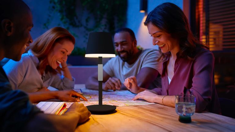 Philips Hue Go Smart Light being used by four people to read a map at night on a wooden table