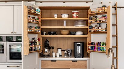 Pink kitchen with open pantry showing spices and appliances,