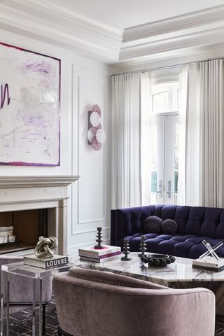 living room with light grey walls, purple sofa, pink chairs and marble coffee table