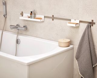 A white bathtub with metal strip panel and small white shelves