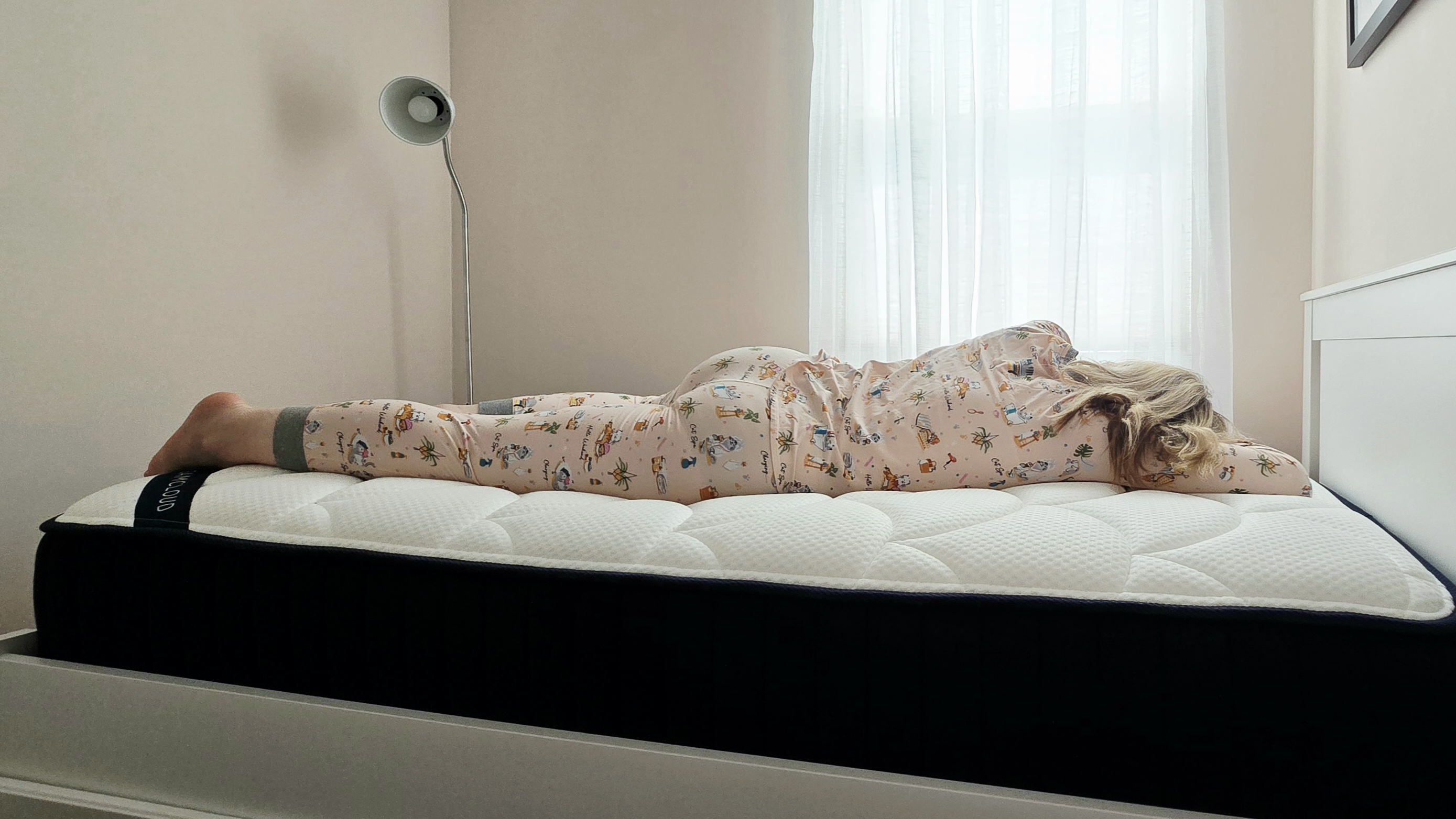 Mattress tester in cat pajamas rests on her stomach for the DreamCloud Classic Memory Foam Mattress review
