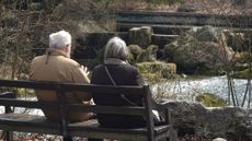 An aging couple sits on a park bench in Bavaria, Germany. 