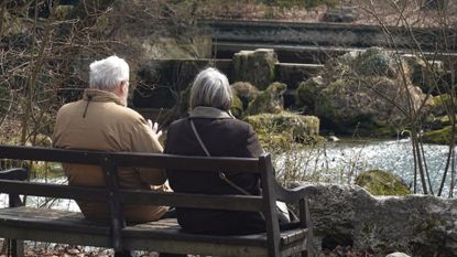 An aging couple sits on a park bench in Bavaria, Germany. 