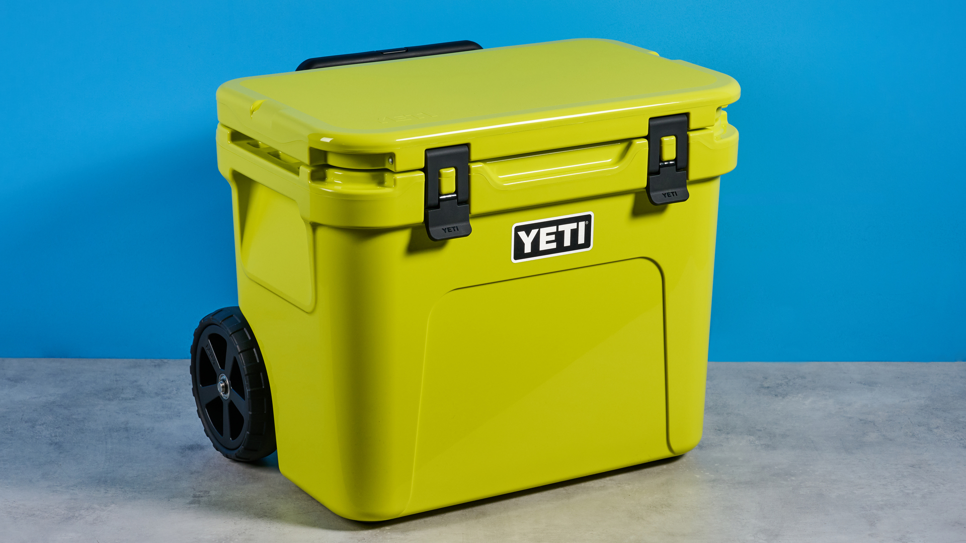 the yeti roader cooler in neon yellow with wheels, soft close hinges, a retractable handle, and 32 quart capacity