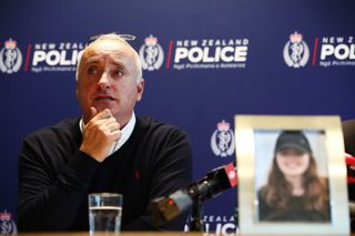 David Millane at a police press conference giving a speech, with a photo of his daughter in front of him