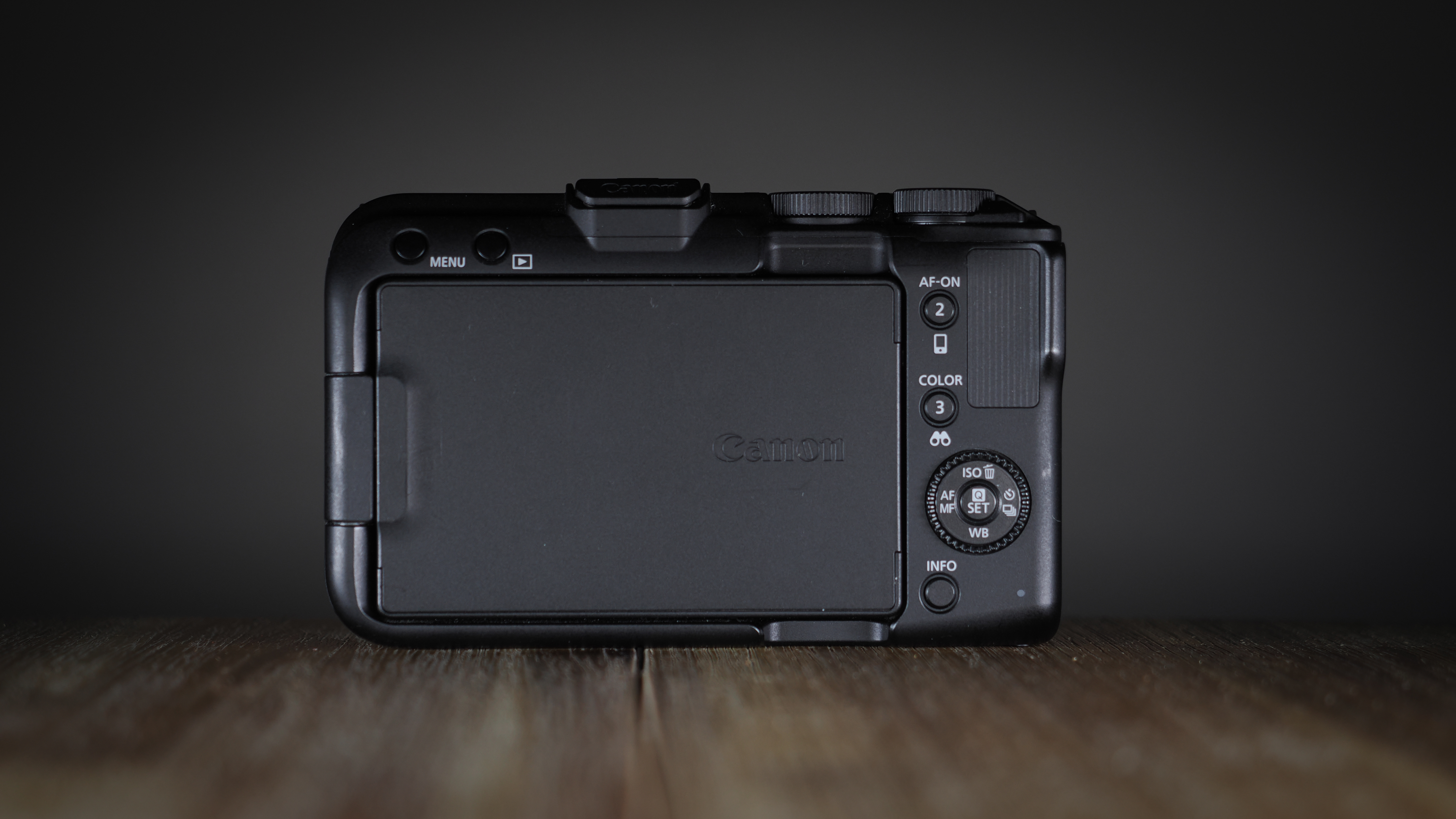 Canon EOS R50 V on a wooden surface, against a dark background