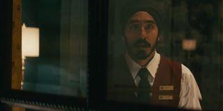 Hotel Mumbai Dev Patel looks out a window with a concerned face