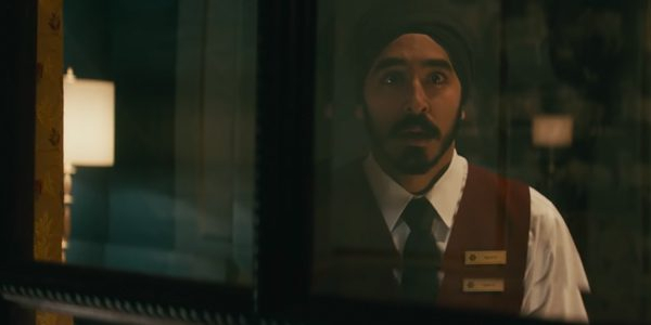 Hotel Mumbai Dev Patel looks out a window with a concerned face